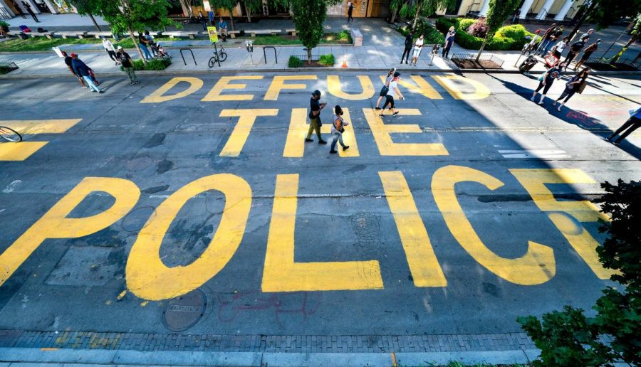 Protesters in Washington write Defund the Police on the street.